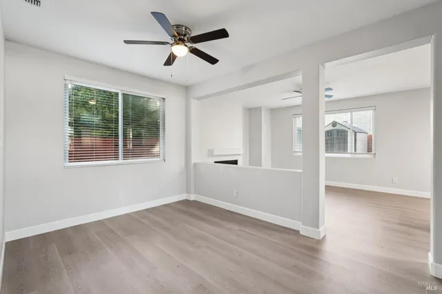 a view of empty room with wooden floor and fan