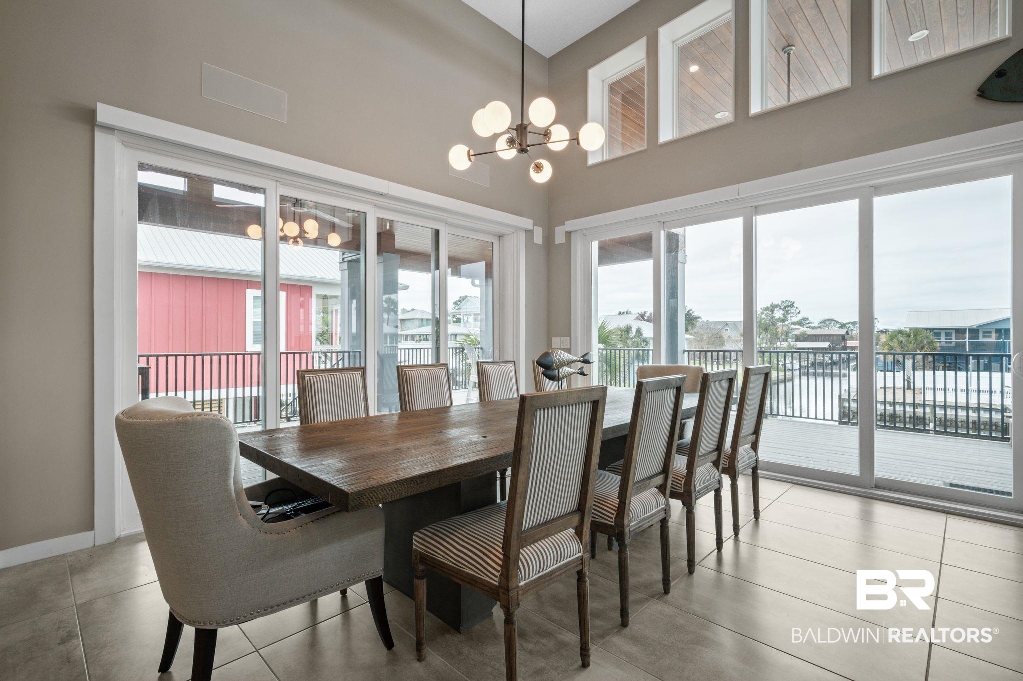 3840 Cotton Way Orange Beach, AL 36561 - Photo 8 of 75 Dining area with tile patterned flooring, a towering ceiling, a water view, and an inviting chandelier