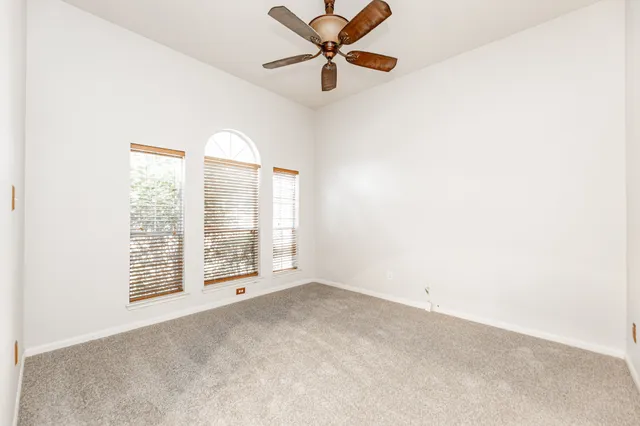 an empty room with windows and ceiling fan