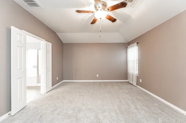 an empty room with chandelier fan and windows