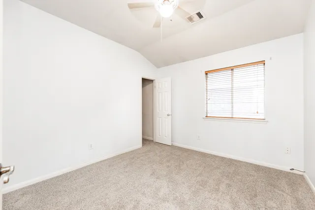 an empty room with windows & fan