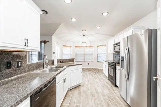 a large kitchen with a center island wooden floor and stainless steel appliances
