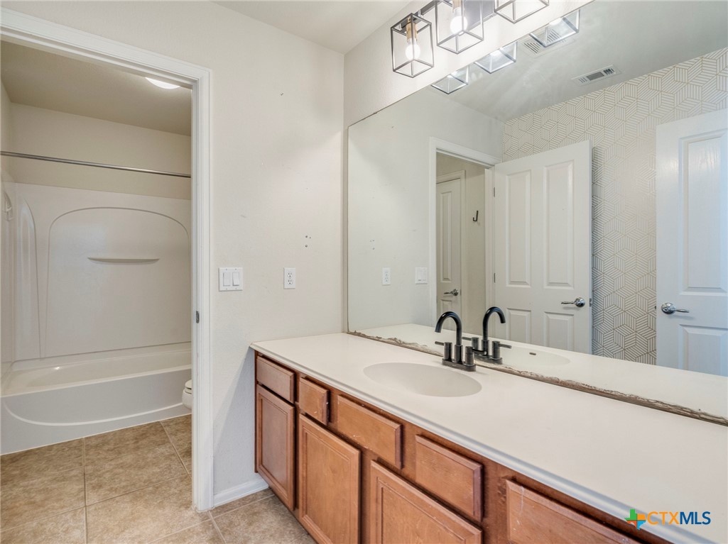 125 Sweet Gum Drive Kyle, TX 78640 - Photo 25 of 31 a bathroom with a sink a large mirror and a bathtub