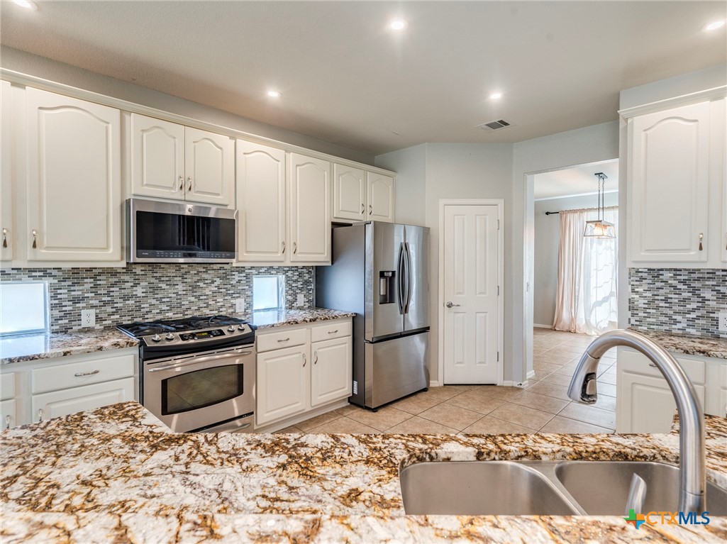 125 Sweet Gum Drive Kyle, TX 78640 - Photo 6 of 31 a kitchen with granite countertop a stove a sink and a refrigerator