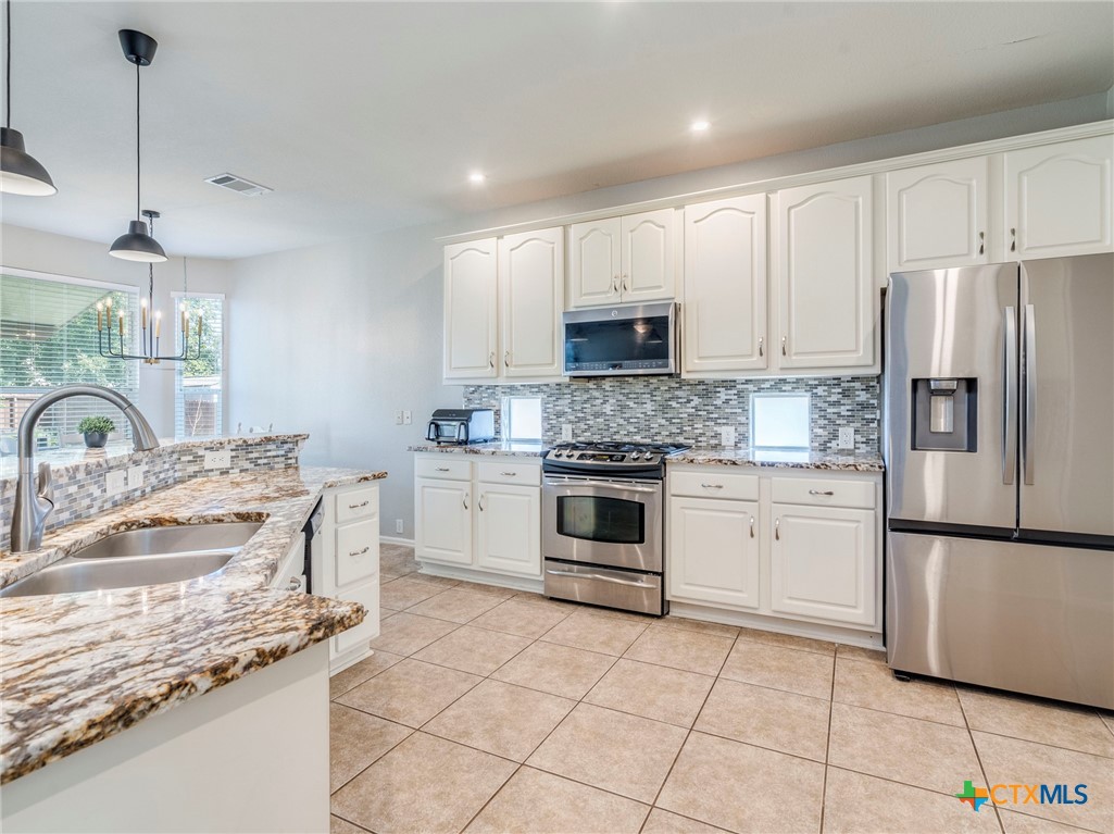 125 Sweet Gum Drive Kyle, TX 78640 - Photo 7 of 31 a kitchen with kitchen island granite countertop a sink appliances and cabinets