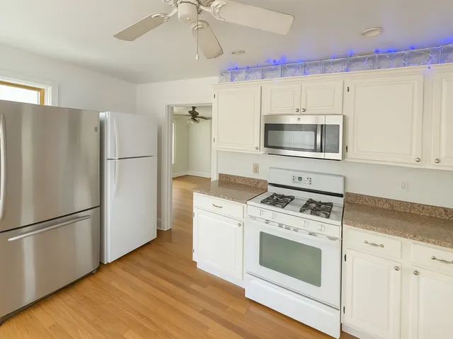 a kitchen with cabinets stainless steel appliances and wooden floor