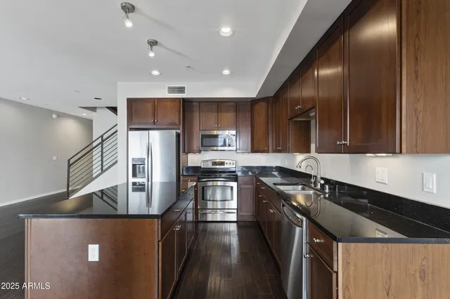 a kitchen with stainless steel appliances granite countertop a sink a stove and a refrigerator