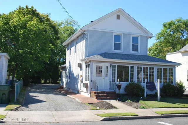 a view of a white house with a yard plants and large tree
