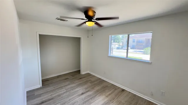 a view of an empty room with wooden floor and a window