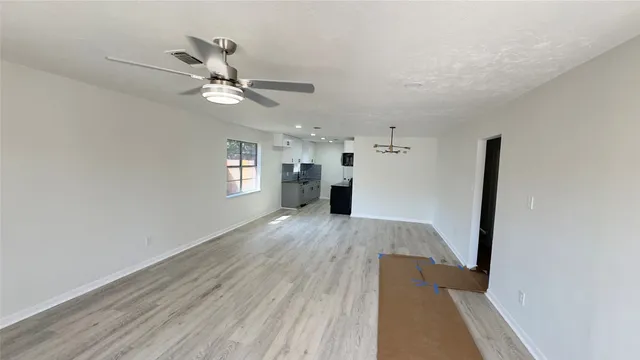 a view of an empty room with window and wooden floor