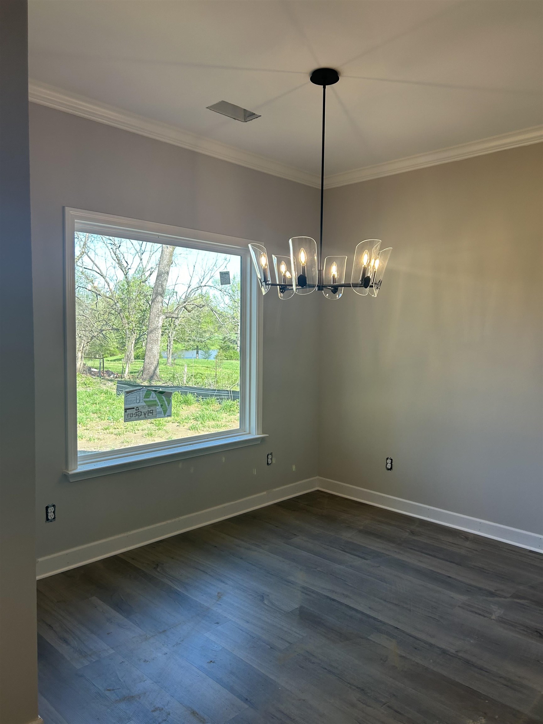 1805 Wortham Road Atoka, TN 38004 - Photo 4 of 20 Unfurnished dining area featuring dark wood-type flooring, crown molding, a notable chandelier, and baseboards