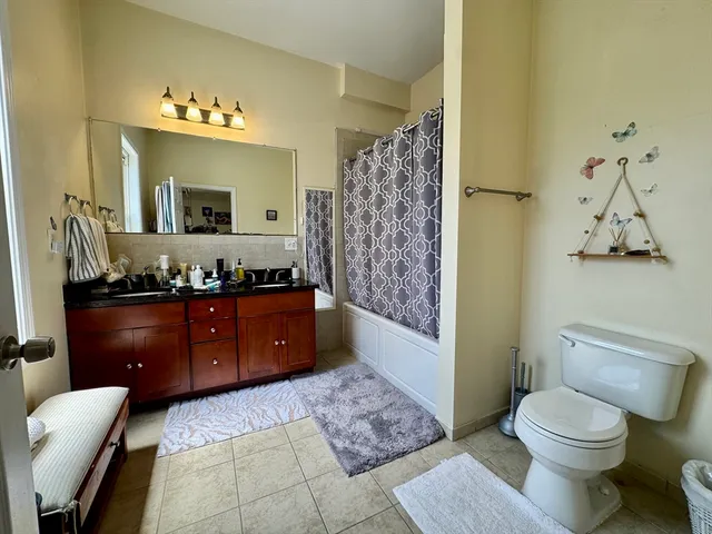 a bed sitting in a bedroom next to a window with chair and dresser