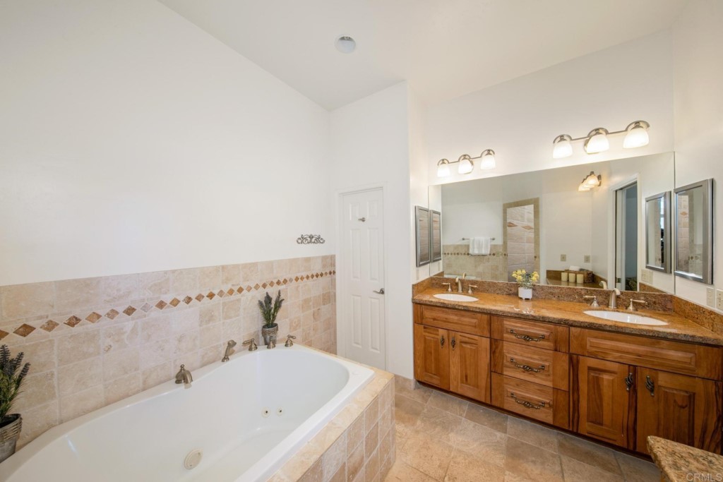 15460 Markar Road Poway, CA 92064 - Photo 19 of 36 a bathroom with a tub a double vanity sink and mirror