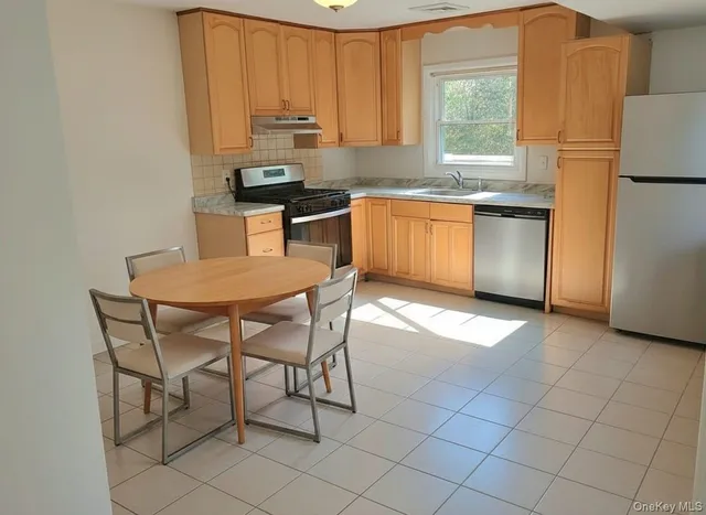a kitchen with stainless steel appliances a stove a sink cabinets and a window