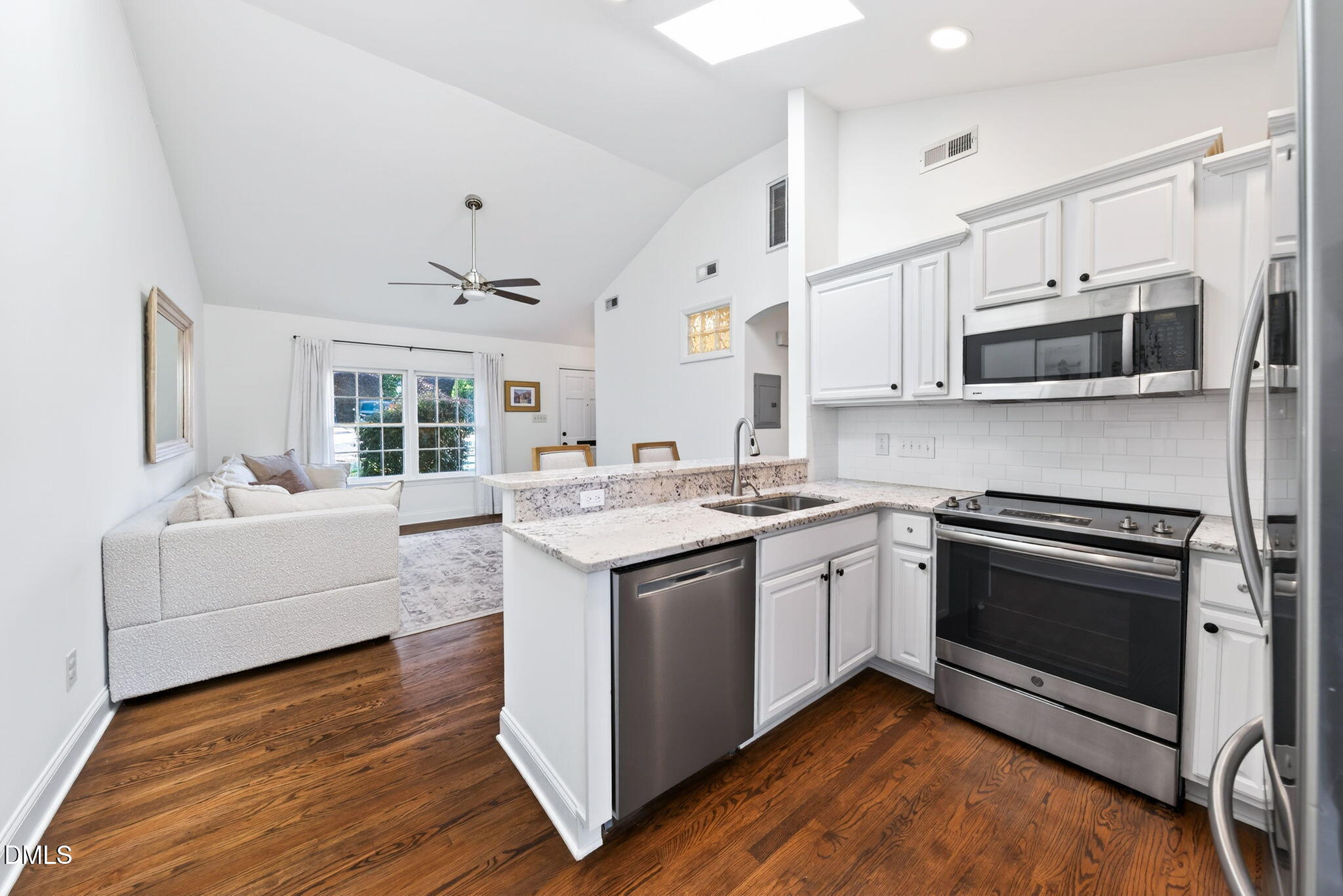 1901 Clark Avenue, Unit 105 Raleigh, NC 27605 - Photo 13 of 28 a kitchen with stainless steel appliances granite countertop a stove top oven a sink dishwasher a microwave oven and a dining table with wooden floor