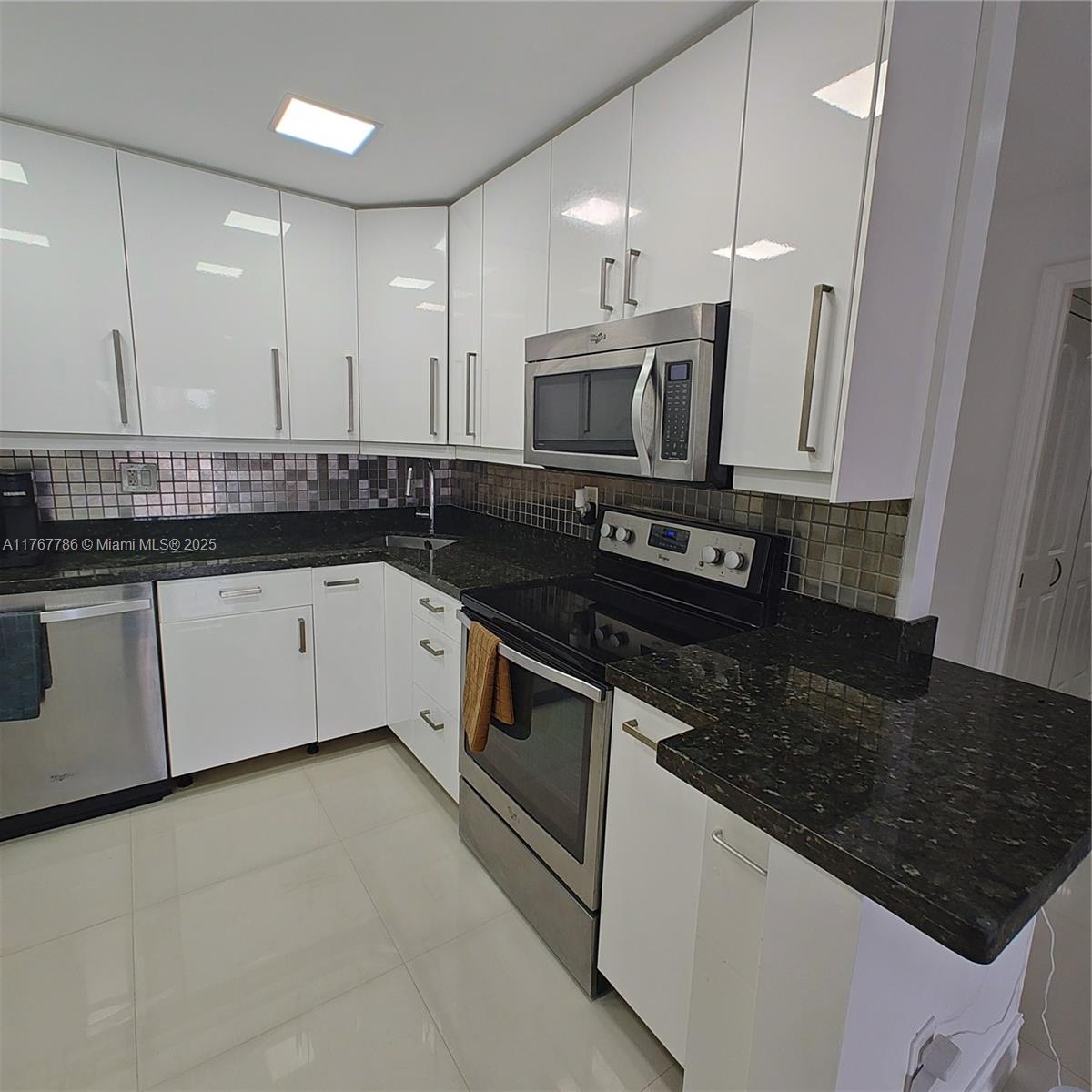 2750 Northeast 183rd Street, Unit 301 Aventura, FL 33160 - Photo 18 of 38 a kitchen with stainless steel appliances granite countertop a stove a sink and a microwave