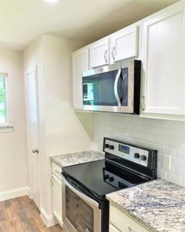 2536 Rutherford Street Irving, TX 75062 - Photo 3 of 19 Kitchen featuring white cabinetry, stainless steel microwave, black glass-top range, light-toned patterned countertops, and white subway tile backsplash