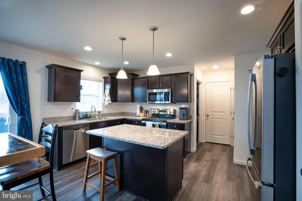 a kitchen with a sink a center island stainless steel appliances and cabinets