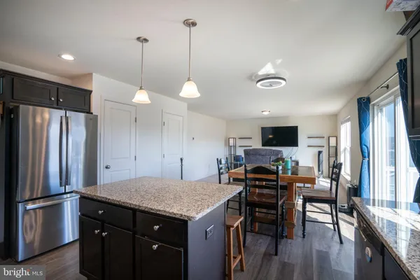 a kitchen with kitchen island a refrigerator a stove a microwave oven a sink with island and chairs
