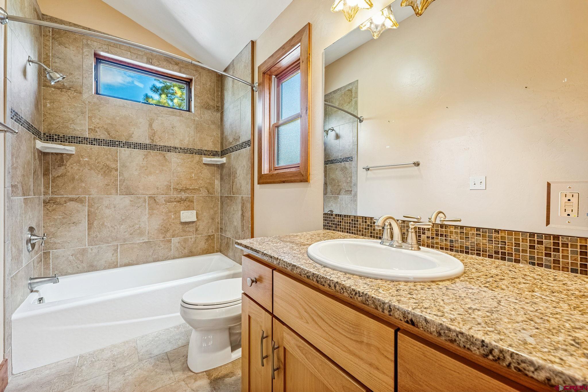 157 Window Lake Trail Durango, CO 81301 - Photo 32 of 39 a bathroom with a granite countertop sink toilet a mirror a bathtub and shower
