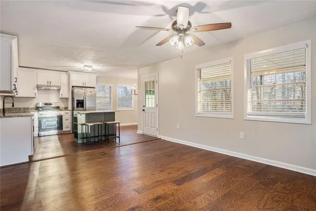 a kitchen with stainless steel appliances kitchen island granite countertop a stove top oven a sink a dining table and chairs with wooden floor