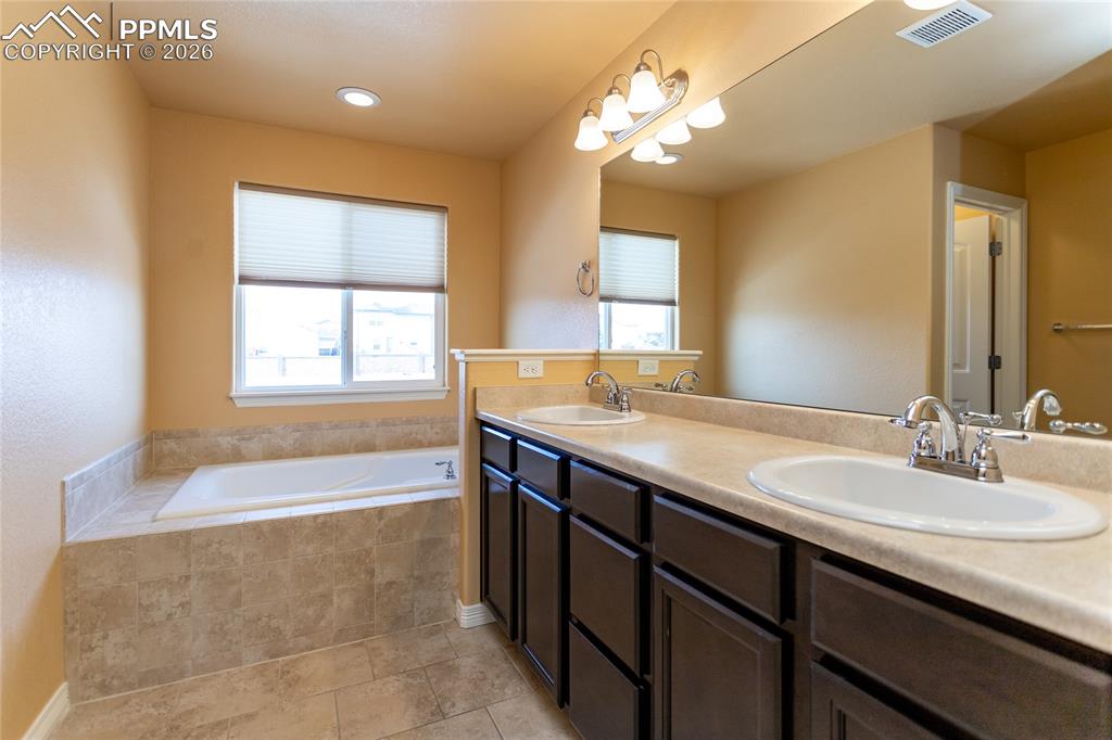 7160 Red Cardinal Loop Colorado Springs, CO 80908 - Photo 17 of 49 a bathroom with a granite countertop sink a bathtub a mirror and a bathtub