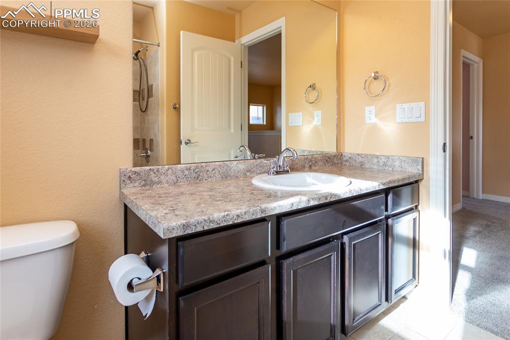 7160 Red Cardinal Loop Colorado Springs, CO 80908 - Photo 23 of 49 a bathroom with a granite countertop sink and a mirror