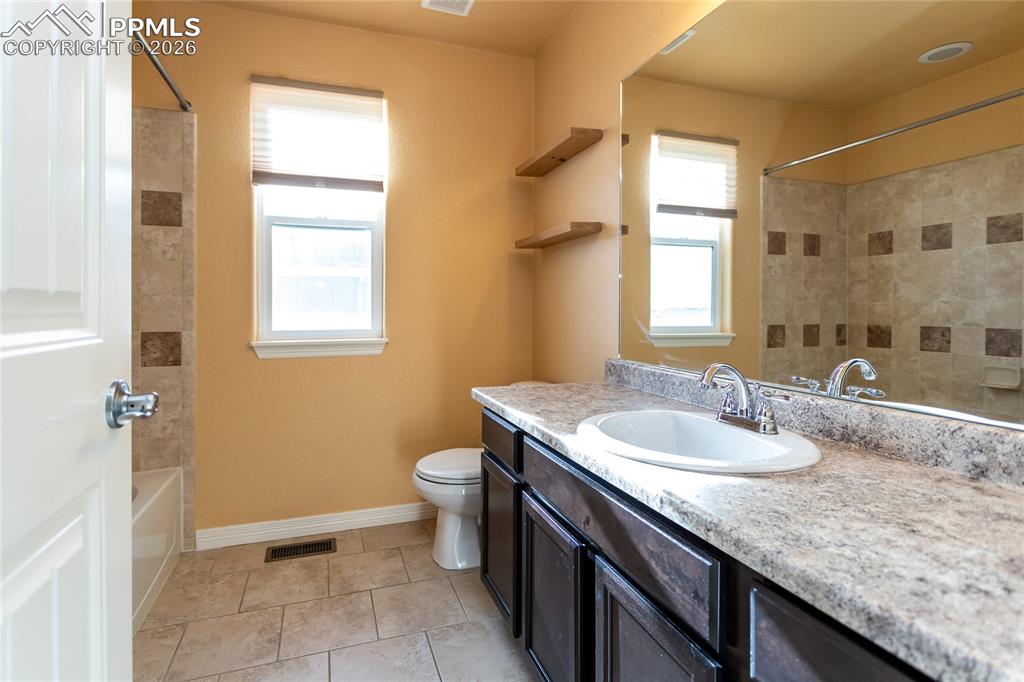 7160 Red Cardinal Loop Colorado Springs, CO 80908 - Photo 24 of 49 a bathroom with a granite countertop sink a toilet and a window