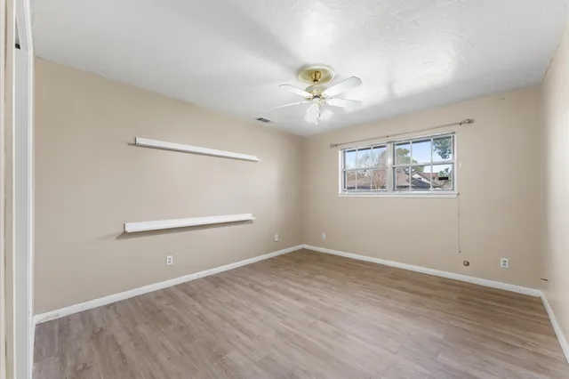 an empty room with windows and fan