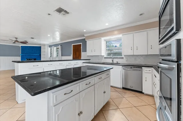 a kitchen with granite countertop a sink stainless steel appliances and white cabinets