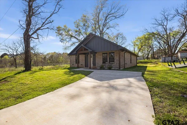 a view of a house with a big yard and large trees