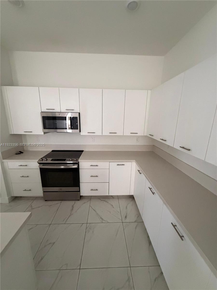 4321 Southwest 173rd Avenue Miramar, FL 33029 - Photo 7 of 28 a kitchen with a white cabinets and white appliances