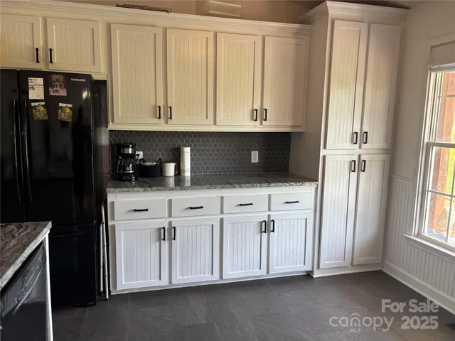 a kitchen with white cabinets and refrigerator