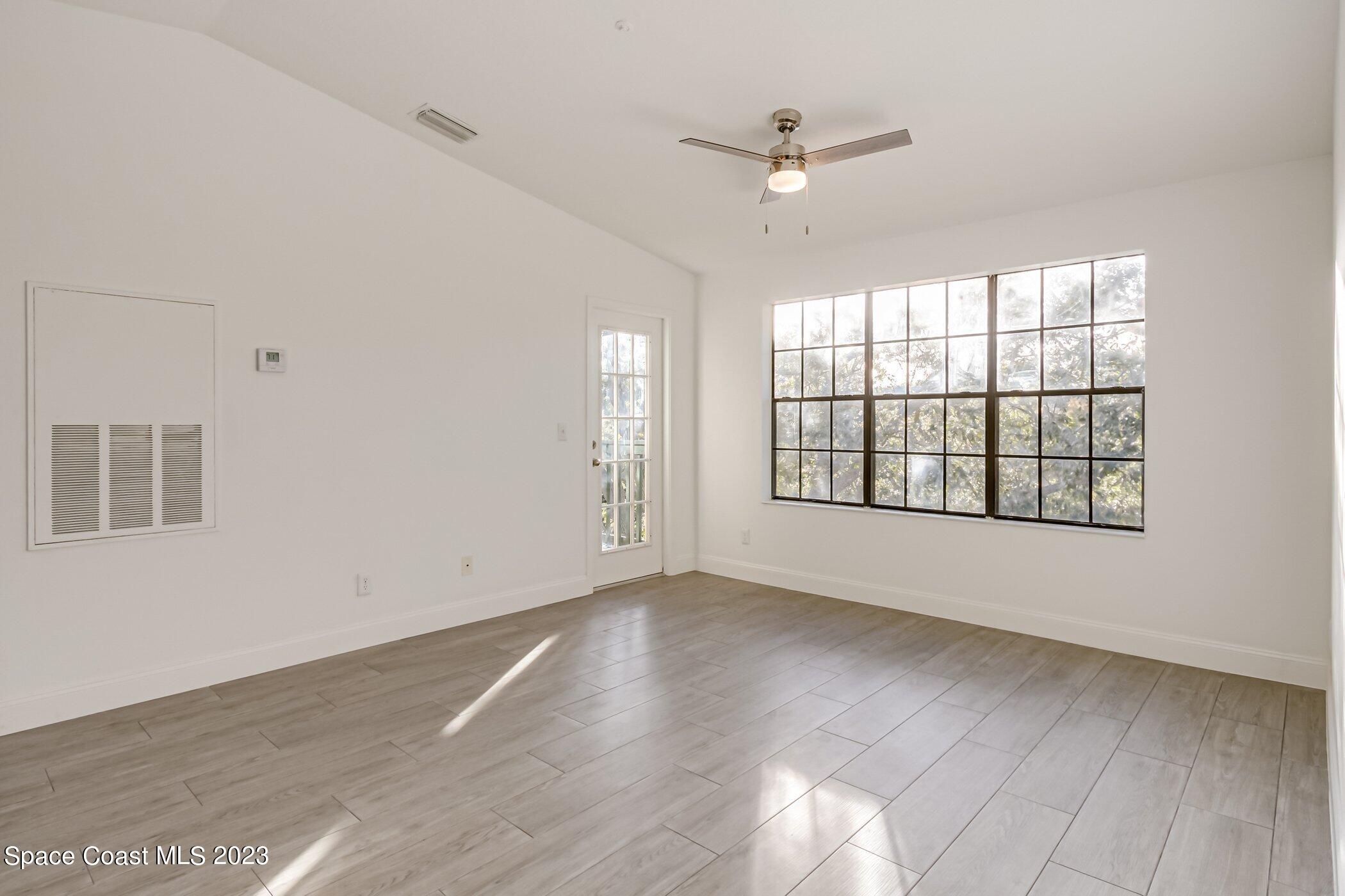 7667 North Wickham Road, Unit 218 Melbourne, FL 32940 - Photo 11 of 35 an empty room with wooden floor fan and windows