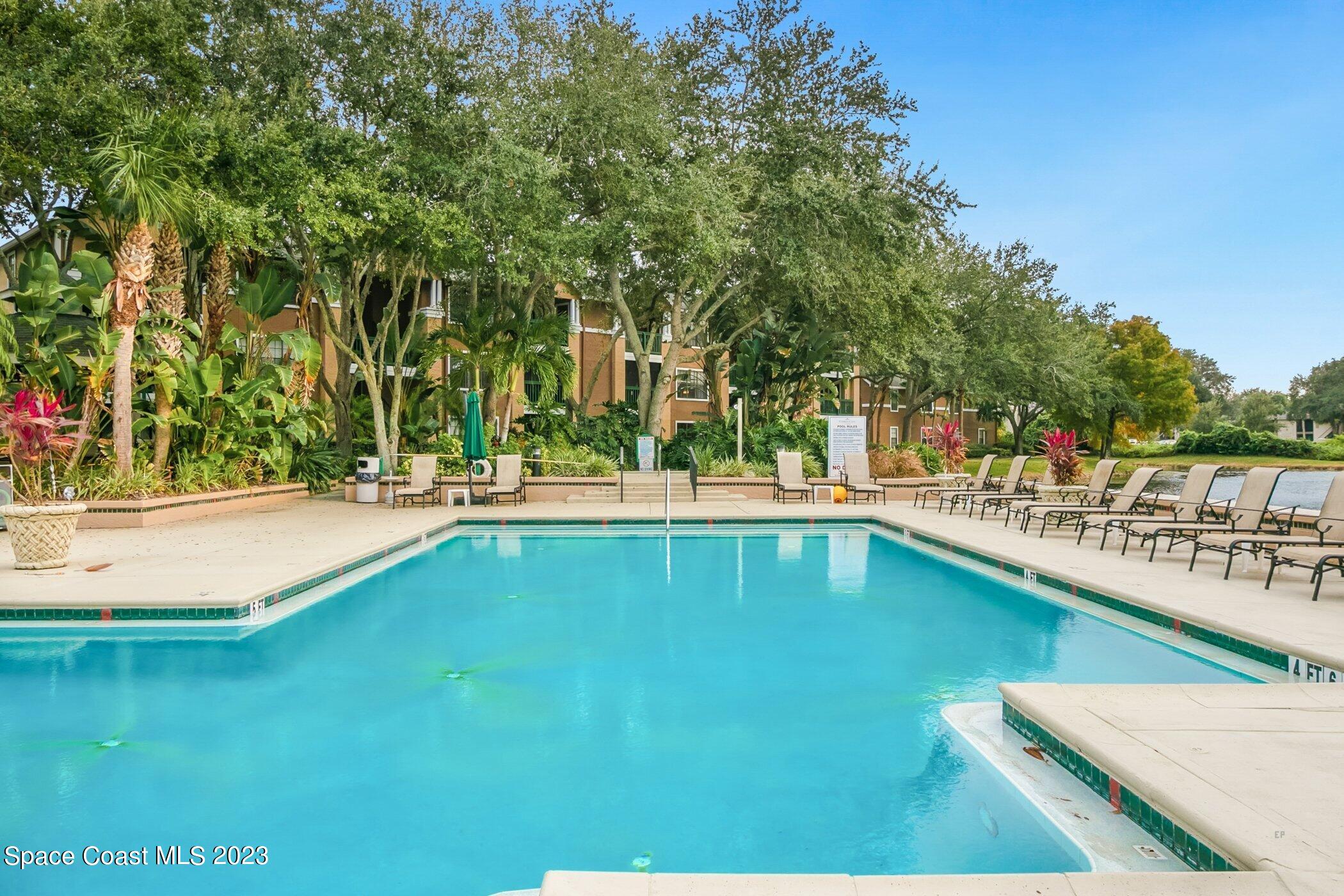 7667 North Wickham Road, Unit 218 Melbourne, FL 32940 - Photo 31 of 35 a view of swimming pool with outdoor seating and trees in the background