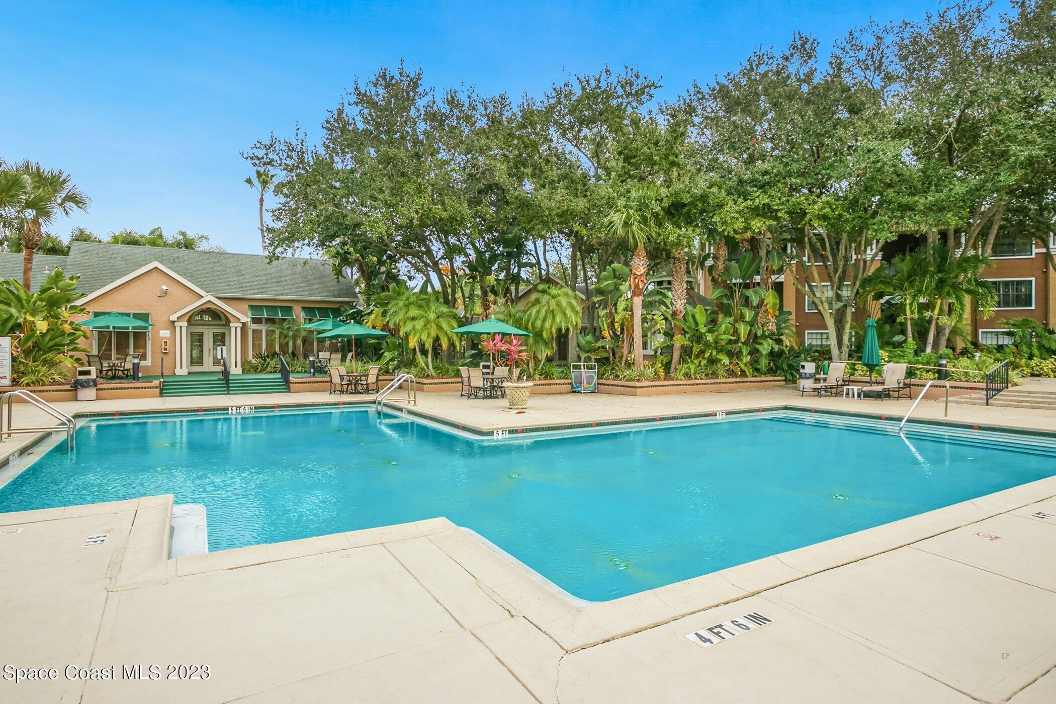 7667 North Wickham Road, Unit 218 Melbourne, FL 32940 - Photo 34 of 35 a view of swimming pool with outdoor seating and trees in the background