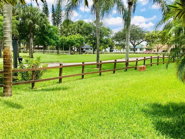 a view of a park with a bench and trees in the background