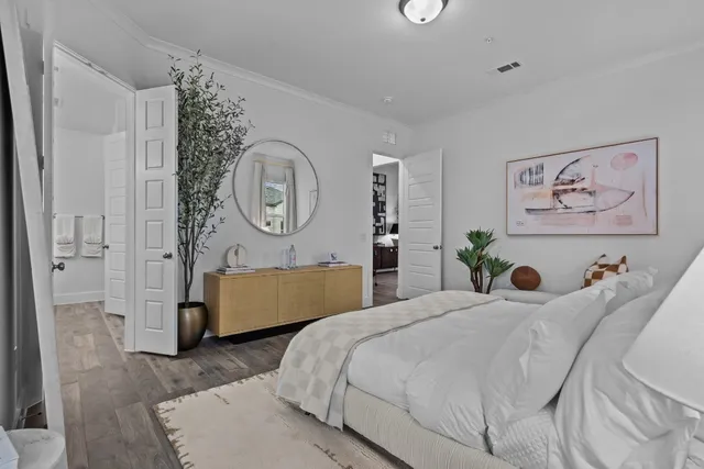 a bedroom with a bed a painting on the wall and a potted plant
