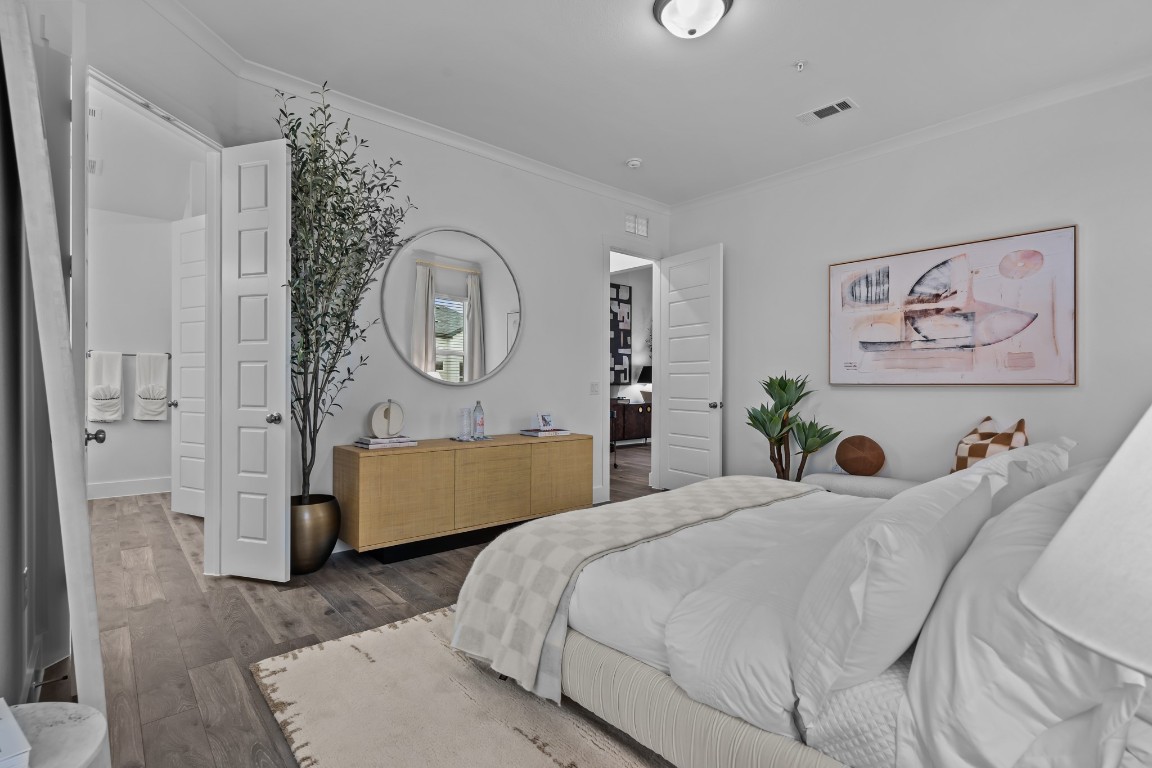 1664 Hillside Terrace, Unit 2117 Buda, TX 78610 - Photo 7 of 33 a bedroom with a bed a painting on the wall and a potted plant