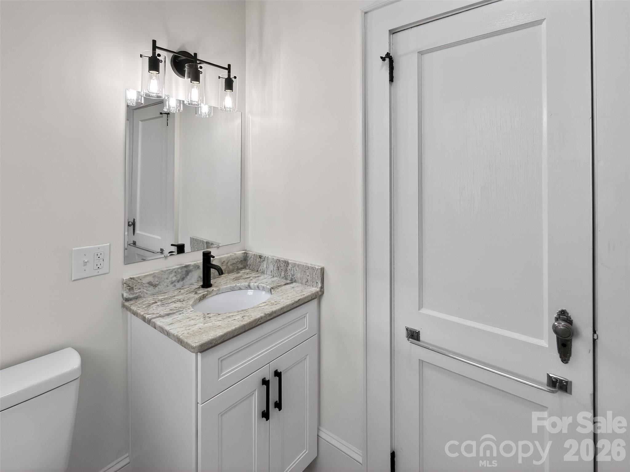262 Pleasant Street Spindale, NC 28160 - Photo 26 of 37 a bathroom with a granite countertop sink a toilet and a mirror