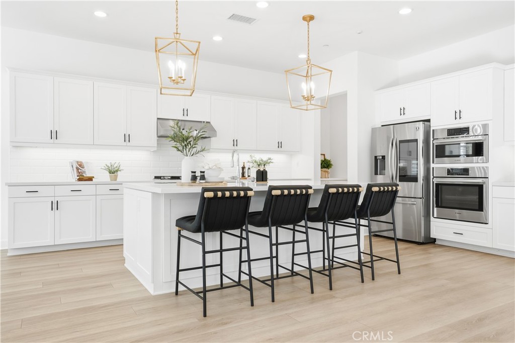 135 Medano Street Rancho Mission Viejo, CA 92694 - Photo 9 of 67 a kitchen with a dining table chairs stainless steel appliances and cabinets