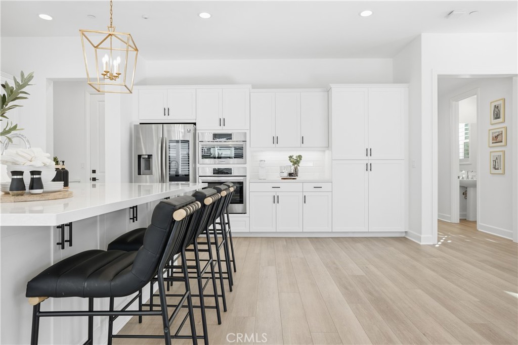 135 Medano Street Rancho Mission Viejo, CA 92694 - Photo 10 of 67 a view of a kitchen with kitchen island white cabinets and stainless steel appliances