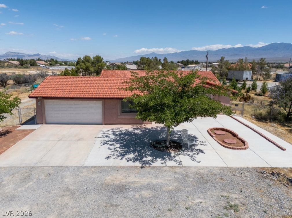 1220 East Gamebird Road Pahrump, NV 89048 - Photo 42 of 49 A single-story home with a terracotta roof, a generous concrete driveway, and distant mountain vistas.