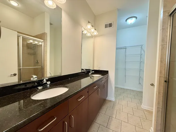 a bathroom with a granite countertop sink a mirror and a shower