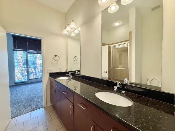 a bathroom with a granite countertop sink a large mirror and a shower