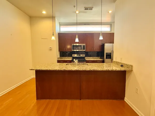 a view of kitchen with stainless steel appliances granite countertop sink and wooden floor