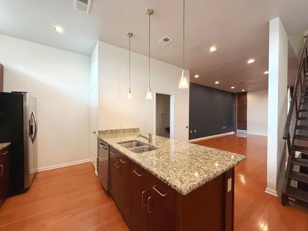 a kitchen with stainless steel appliances granite countertop stove top oven a refrigerator and a dining table with wooden floor