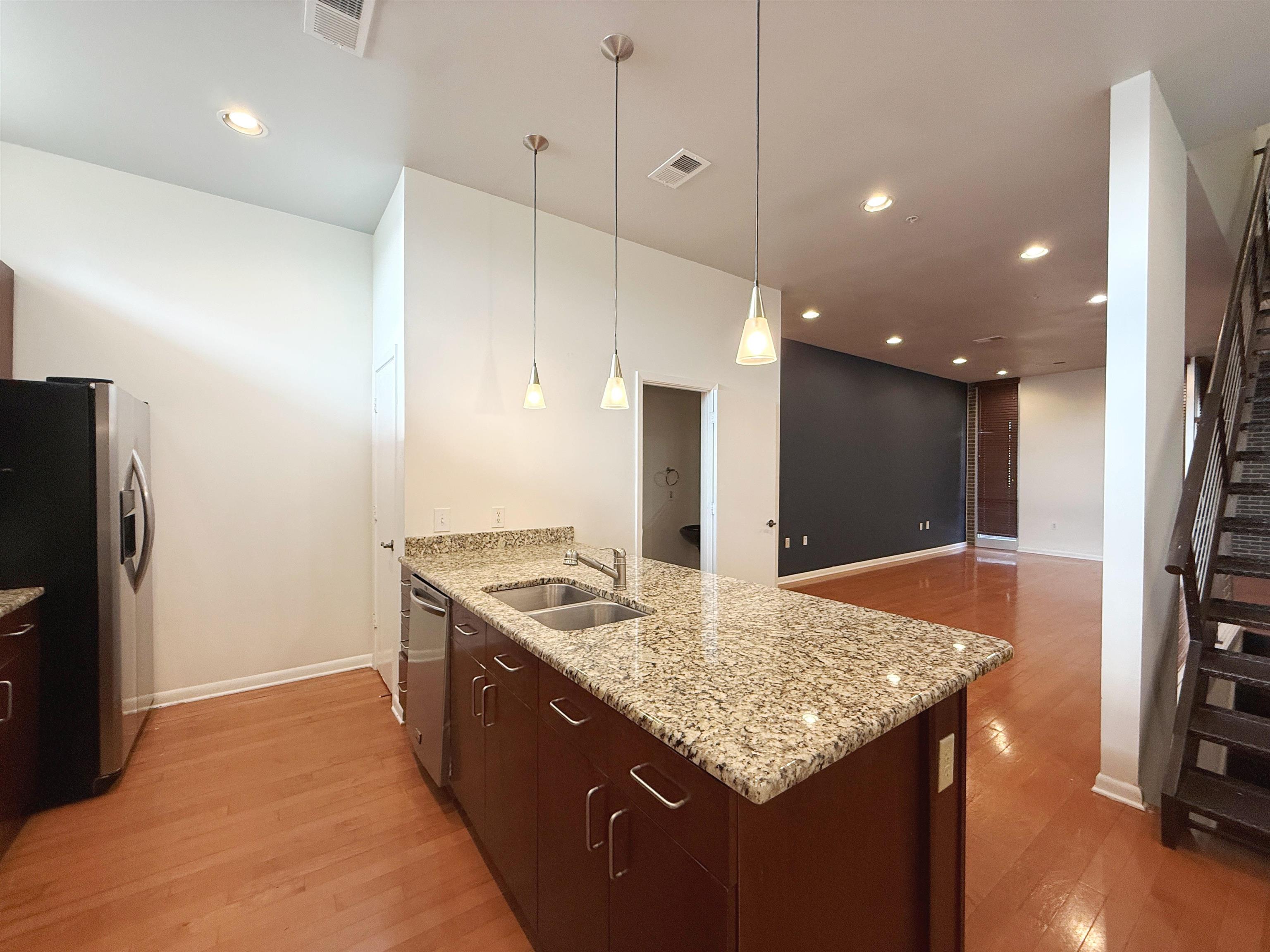 449 Monroe Avenue, Unit 104 Memphis, TN 38103 - Photo 5 of 24 a kitchen with stainless steel appliances granite countertop stove top oven a refrigerator and a dining table with wooden floor