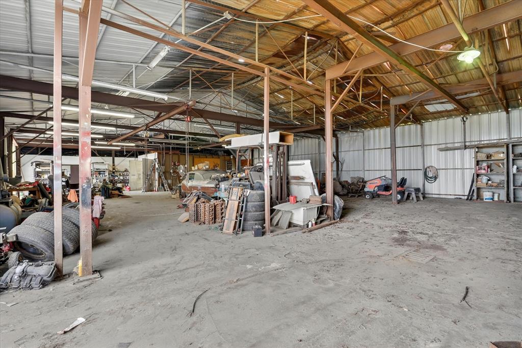 1092 West Highway 199 Springtown, TX 76082 - Photo 25 of 29 Spacious garage featuring a high ceiling, exposed metal beam construction, corrugated metal wall panels, and a concrete floor