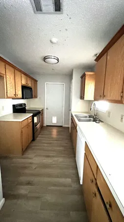 a large kitchen with a stove top oven a sink a counter space and cabinets